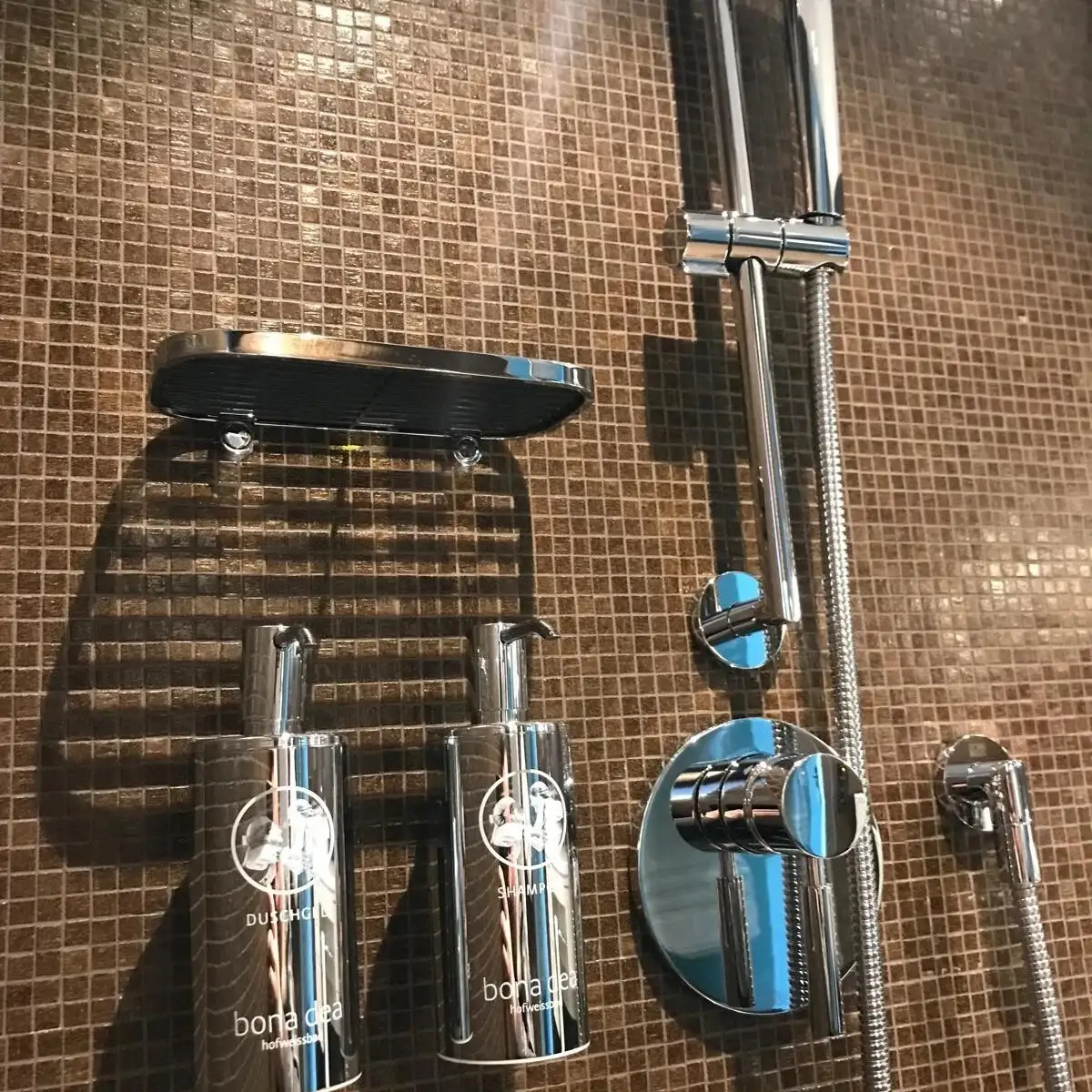 Dusche mit braunem Mosaik und Armaturen